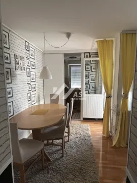 Trpezarija sa drvenim stolom i stolicama, ukrašena zidom od cigle i brojnim ramovima za slike. - image 5