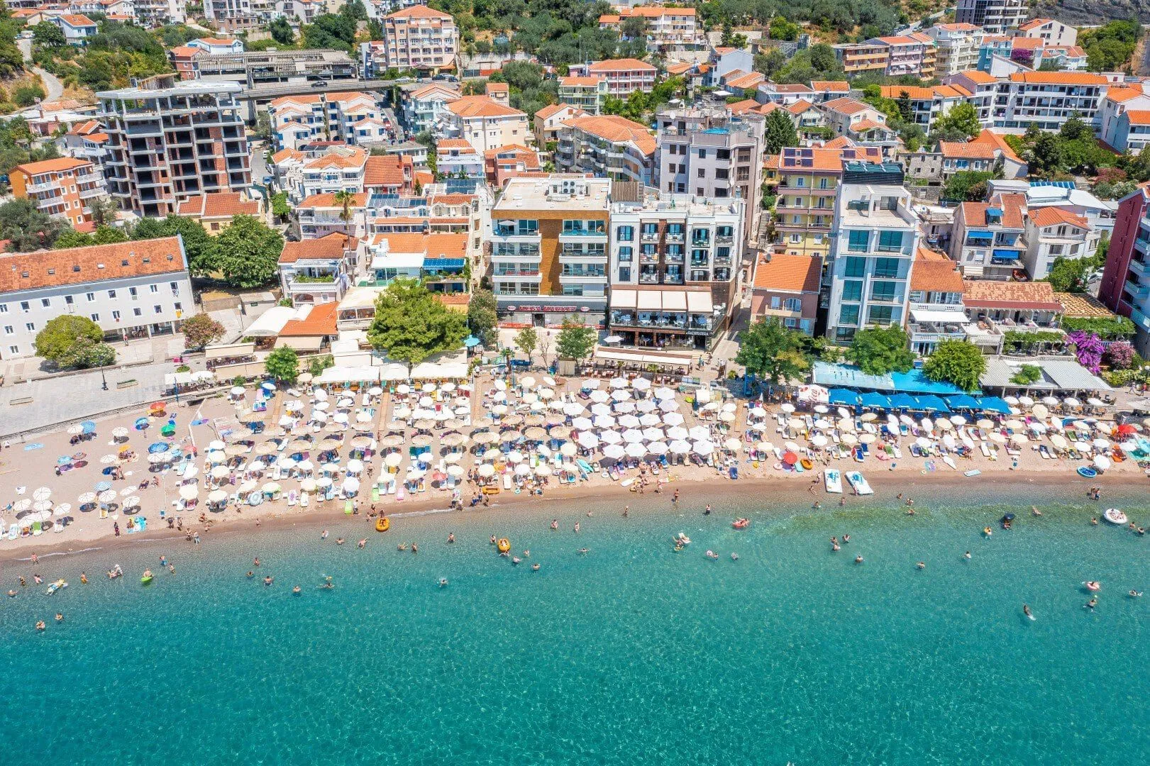 Pogled iz vazduha na pješčanu plažu i naselje uz obalu.