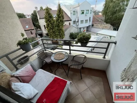 Namešten balkon sa garniturom za sedenje i pogledom na okolne zgrade. - image 10