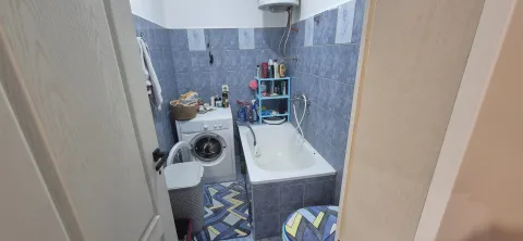 Manje kupatilo sa kadom, veš mašinom i plavim pločicama. - image 3