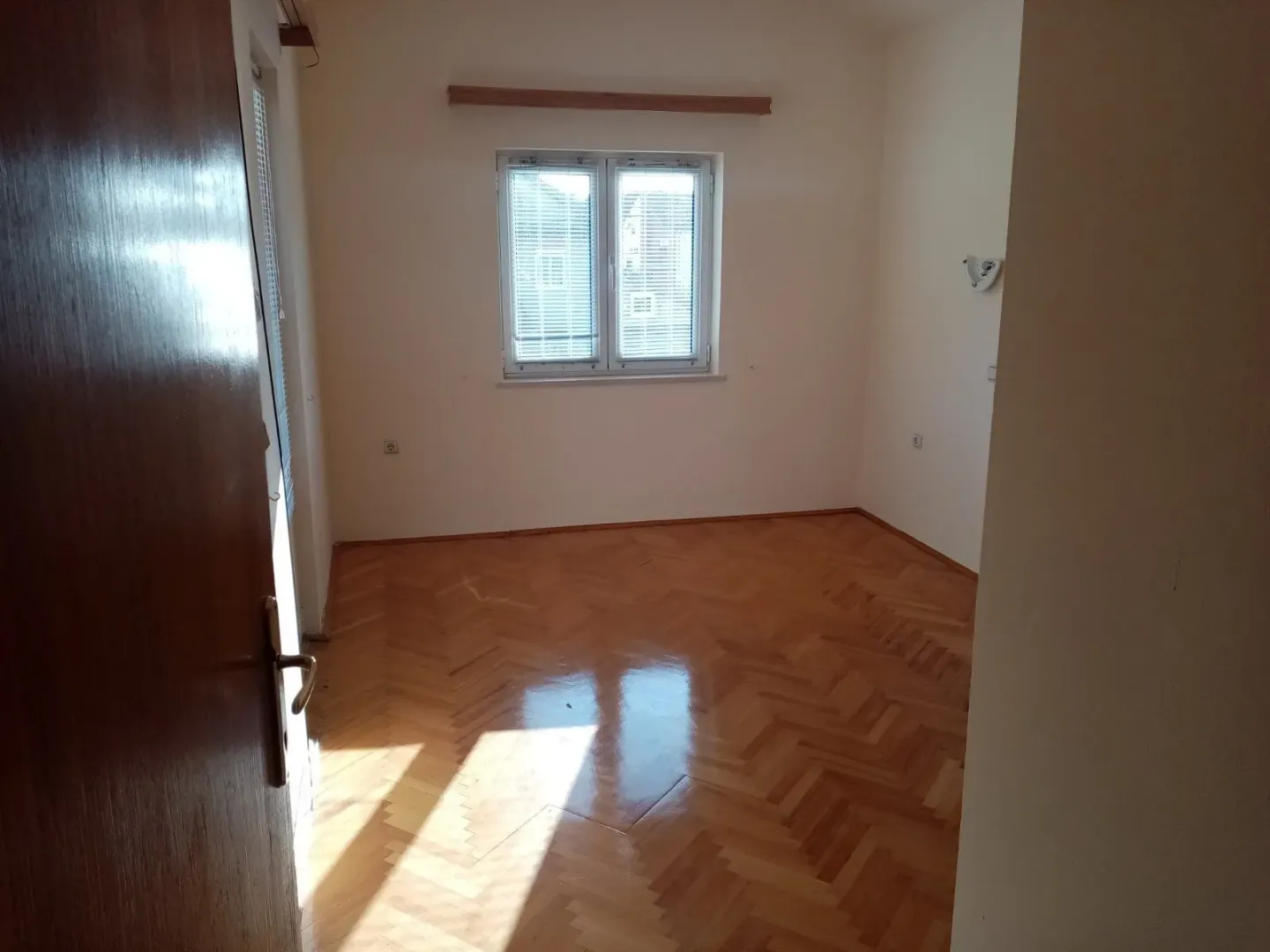 Empty room with parquet flooring.