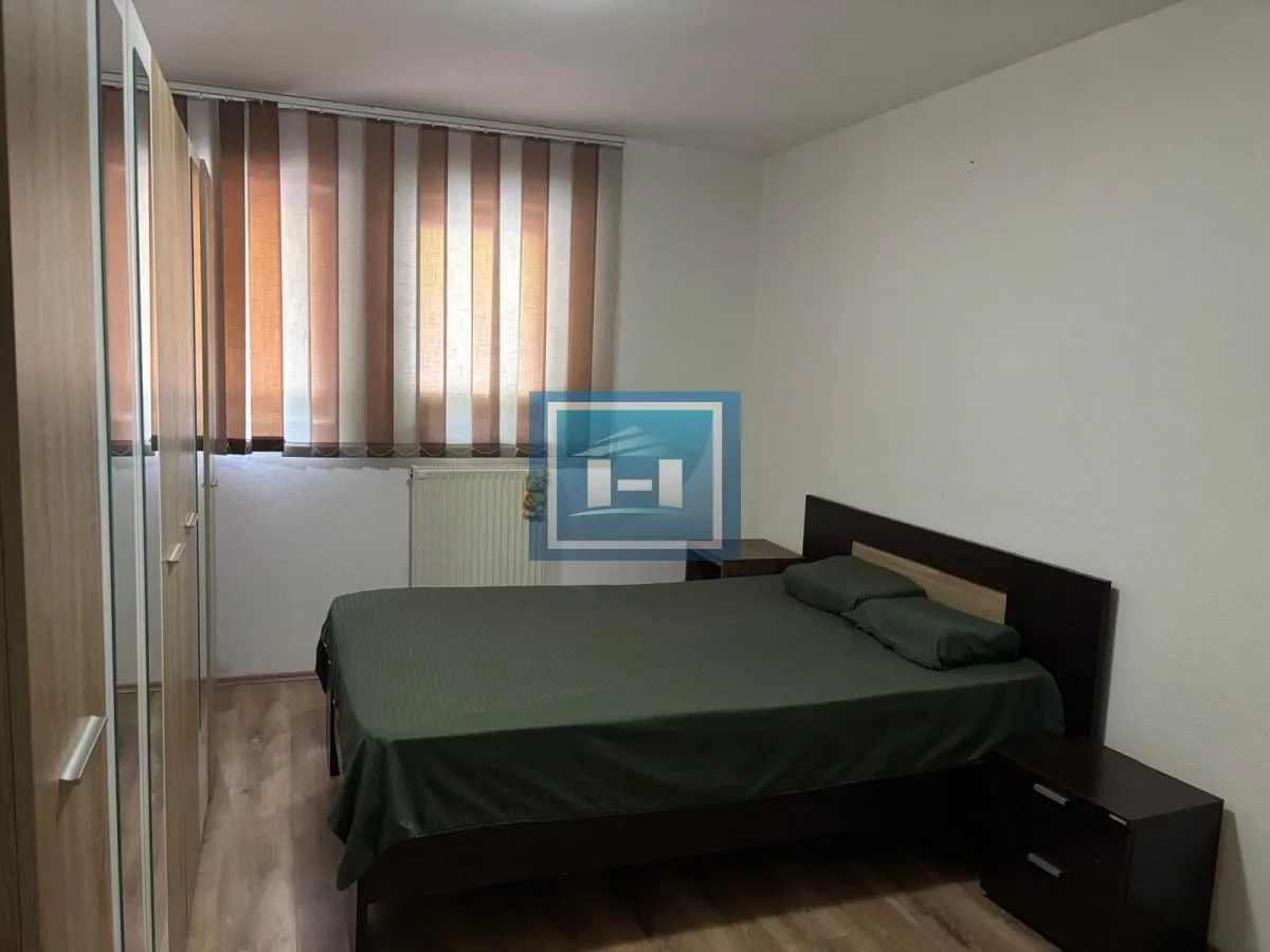 Spavaća soba sa bračnim krevetom, plakarom i prozorom sa roletnama.