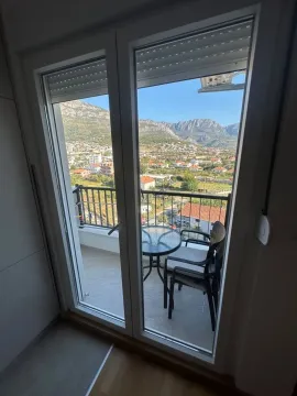 View through the balcony door to the terrace and surrounding landscape with mountains. - image 5