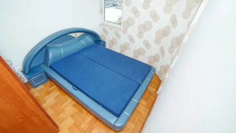 Bright bedroom with a large blue bed and parquet flooring. - image 7