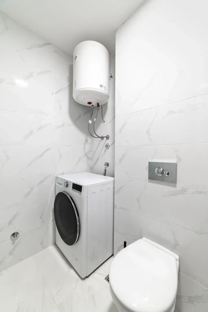 Moderno opremljeno kupatilo sa veš mašinom i bojlerom.