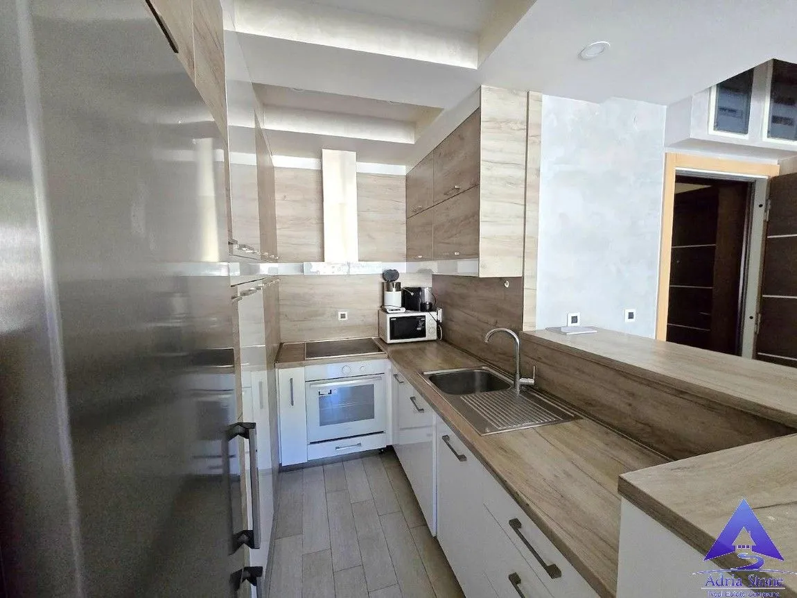 Moderna kuhinja sa drvenim elementima i ugrađenim kućnim aparatima.