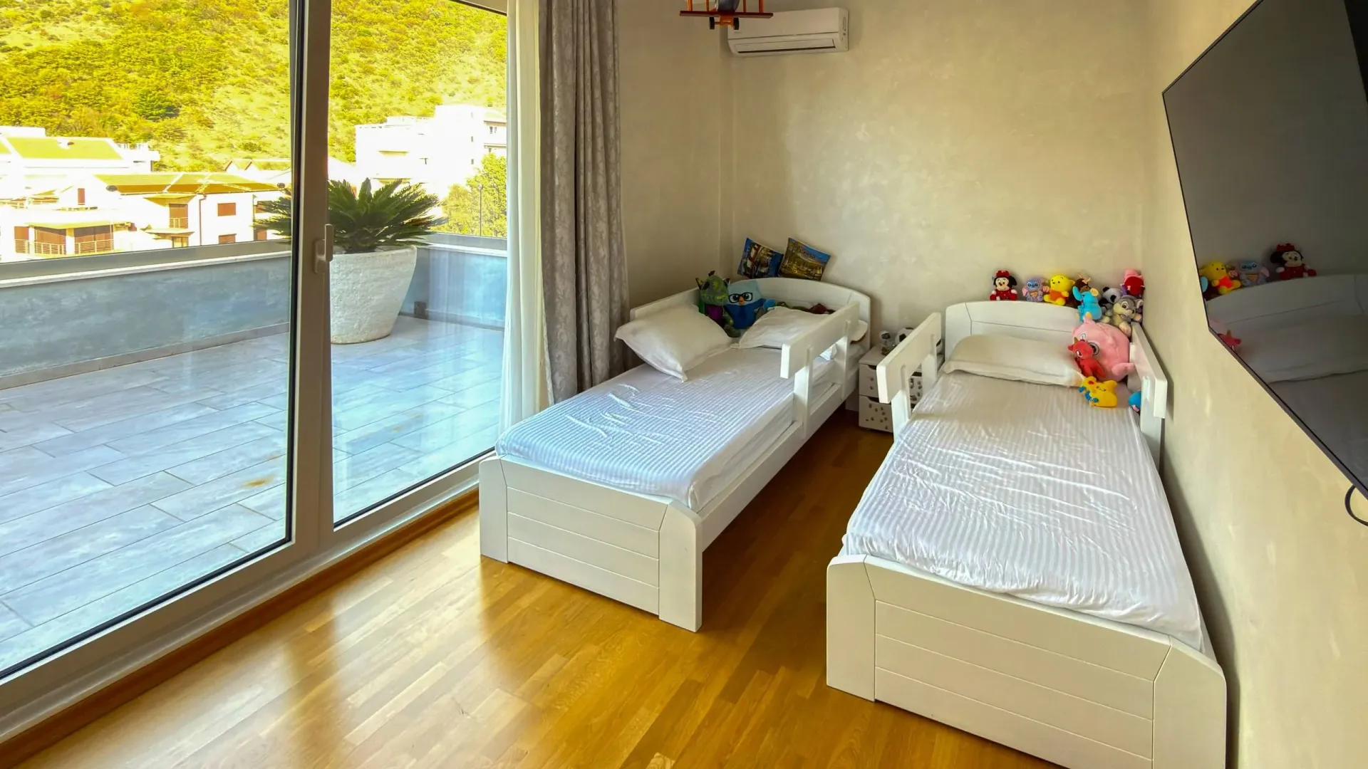 Dječja spavaća soba sa dva kreveta i izlazom na terasu.