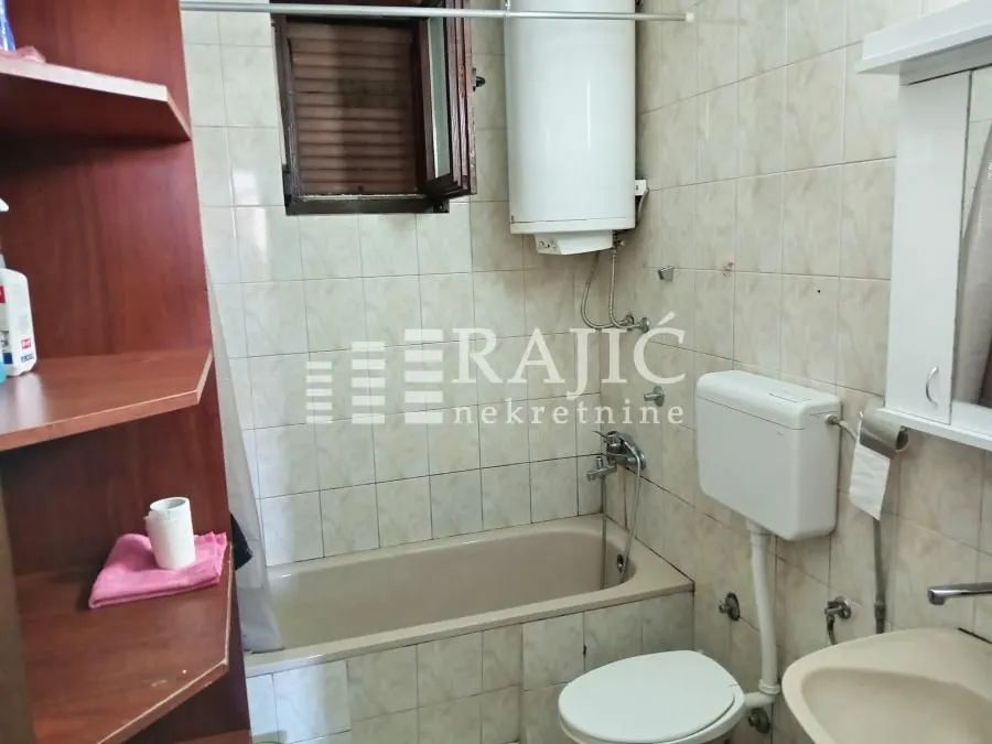 Smaller bathroom with a bathtub, water heater, and sanitary fixtures.