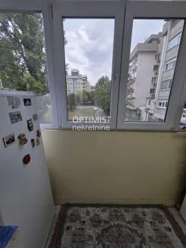 Zastakljena terasa sa frižiderom i pogledom na naselje. - image 10