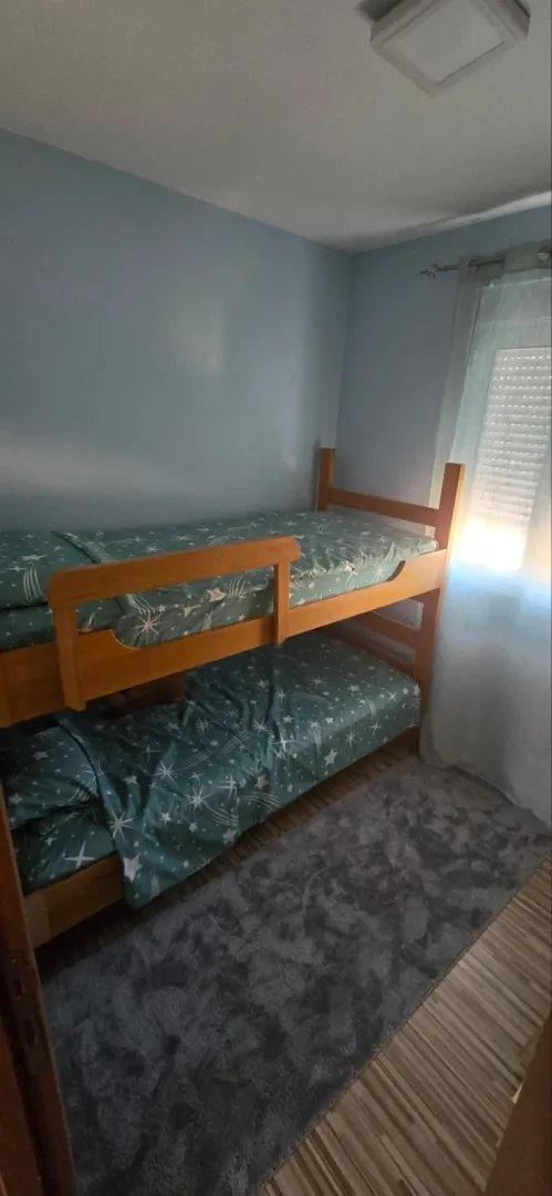Children's bedroom with a wooden bunk bed and a rug.