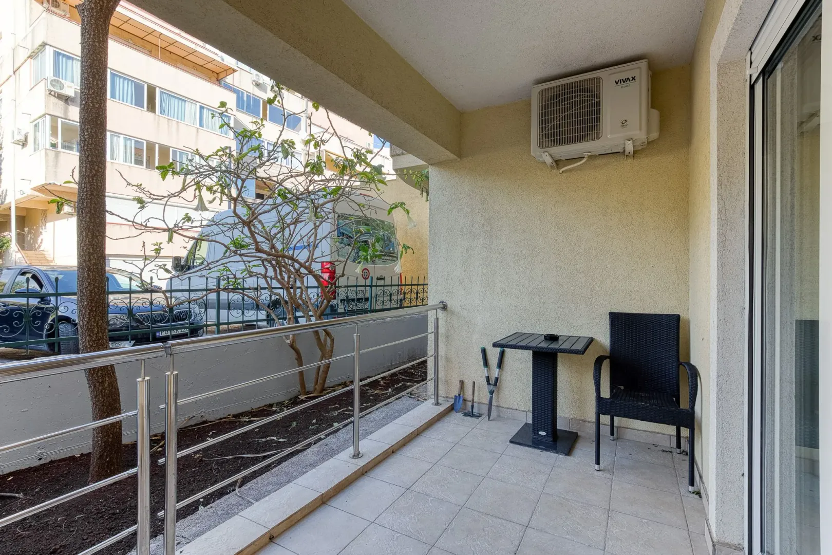 Covered terrace with a table, chair, and air conditioning unit.