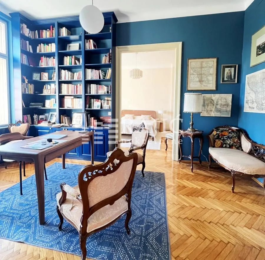 Study room with blue walls, large bookcase and antique furniture.