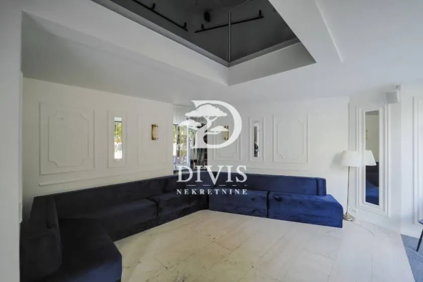 Living room with a large blue corner sofa and decorative wall molding.