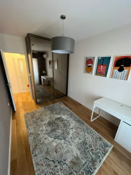 Small bedroom with a large wardrobe, desk, and a rug on the floor. - image 8