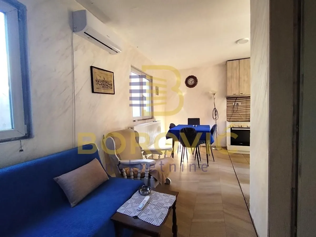 Living room with a sofa, armchair, and dining table in the background.