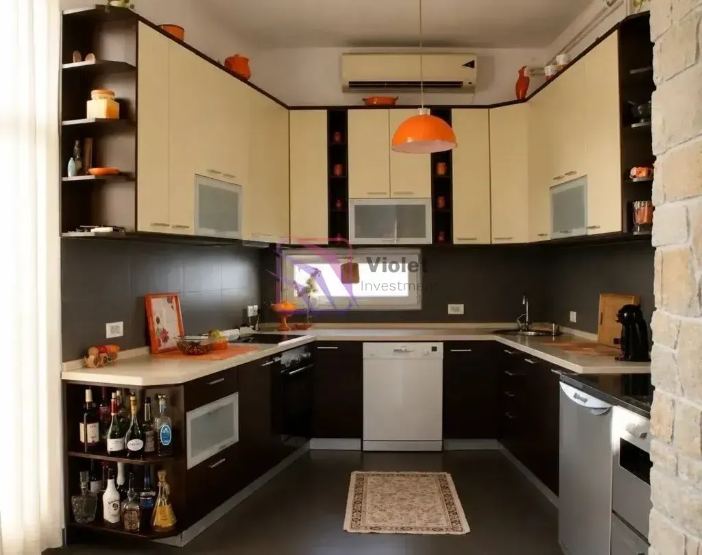 Modern U-shaped kitchen with dark and light cabinets and built-in appliances.
