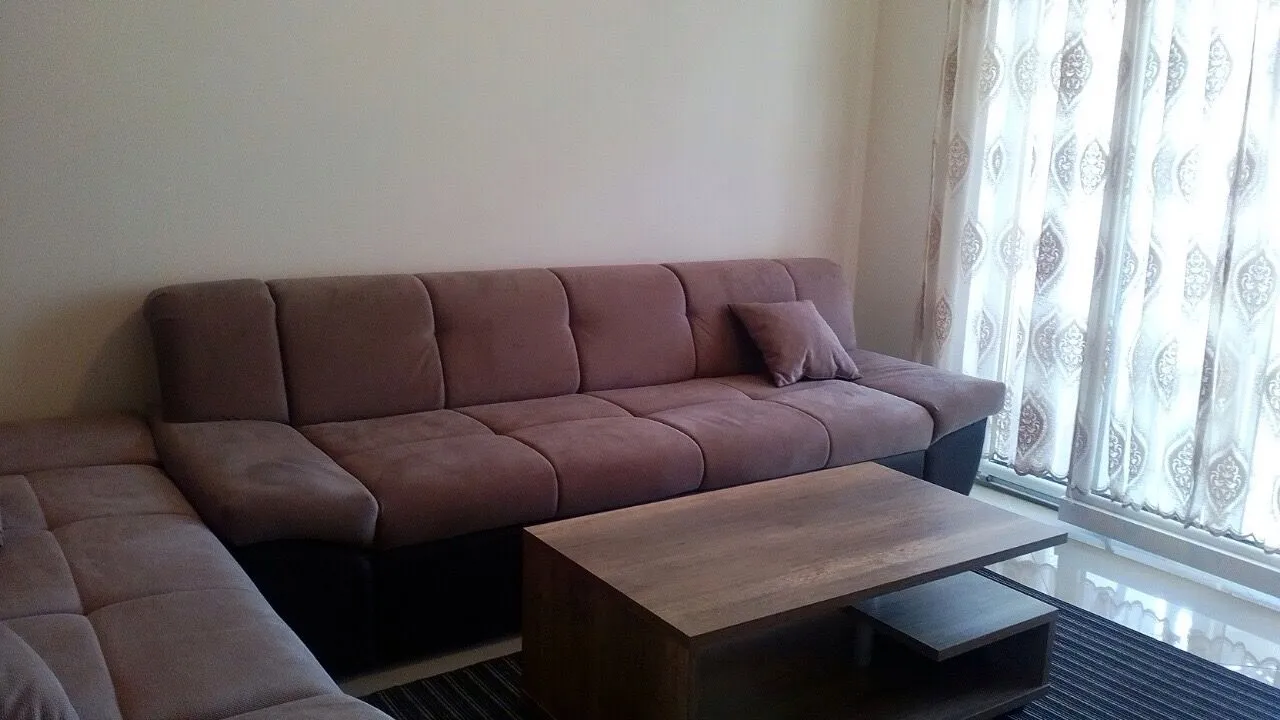 Dnevna soba sa ugaonom garniturom i drvenim stočićem.