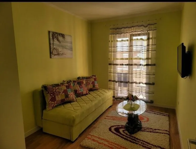 Bright living room with a green sofa and a glass coffee table.