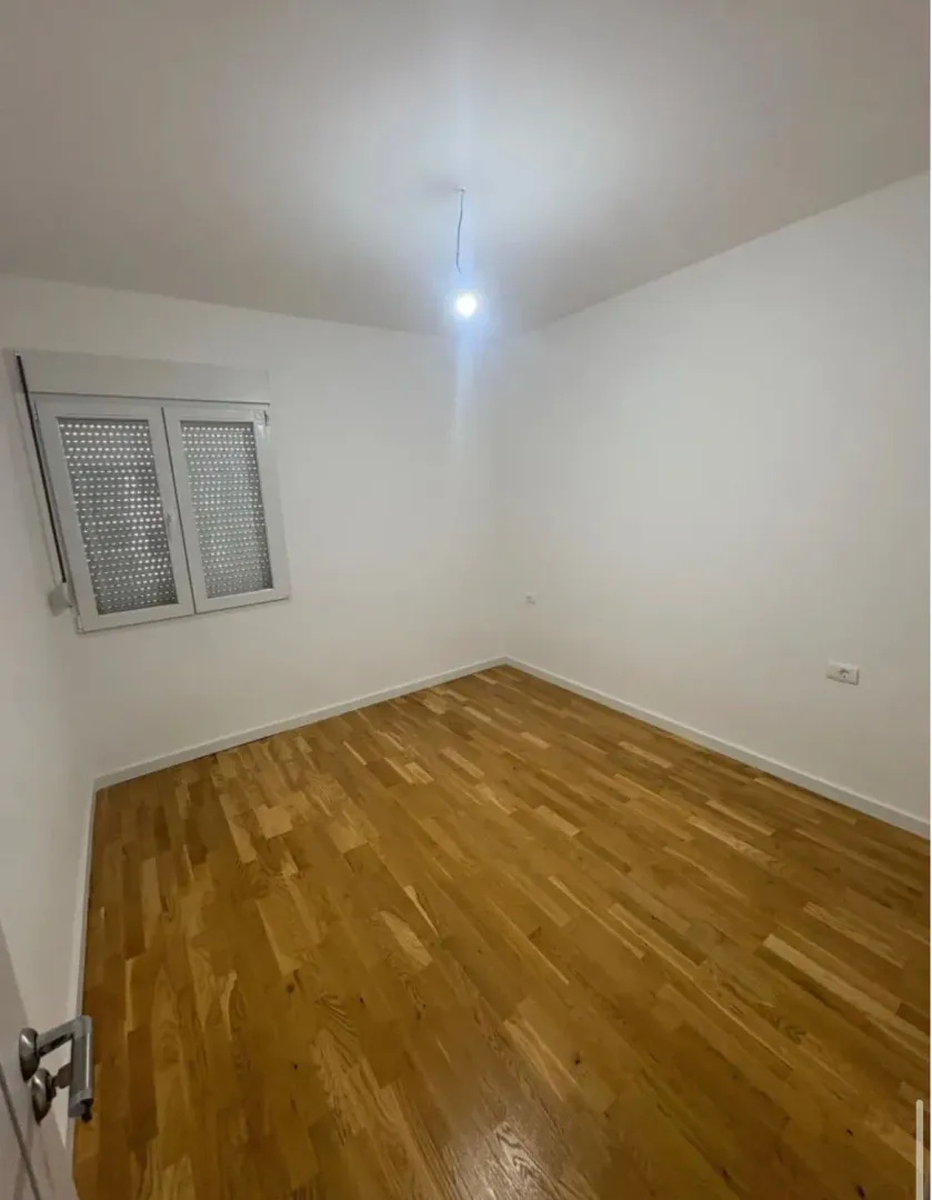 Empty room with white walls and wooden flooring.