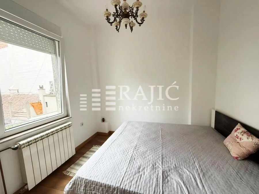 Furnished bedroom with a double bed and a window.