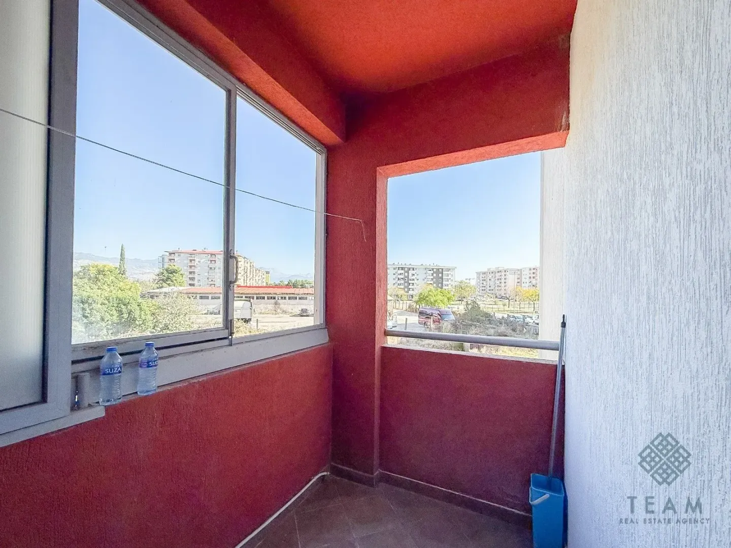 Covered balcony with a view of surrounding buildings and the city.
