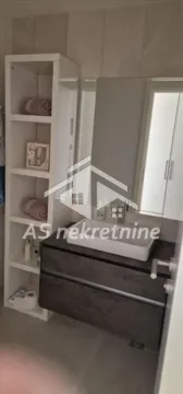 Moderno kupatilo sa umivaonikom, ogledalom i belim regalom za odlaganje. - image 7