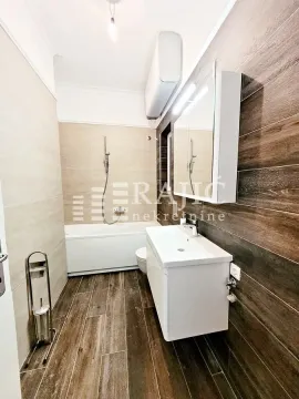 Modern bathroom with a bathtub, washbasin, and wood-effect tiles. - image 10
