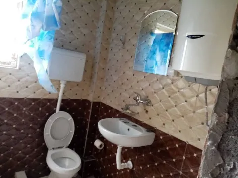 Simple bathroom with toilet, sink, and water heater. - image 15