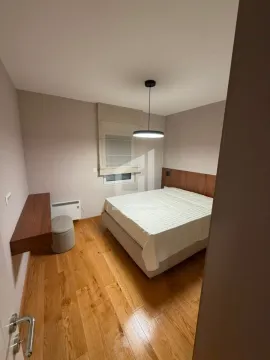 Modern bedroom with a double bed, wooden flooring, and a wall-mounted shelf. - image 8