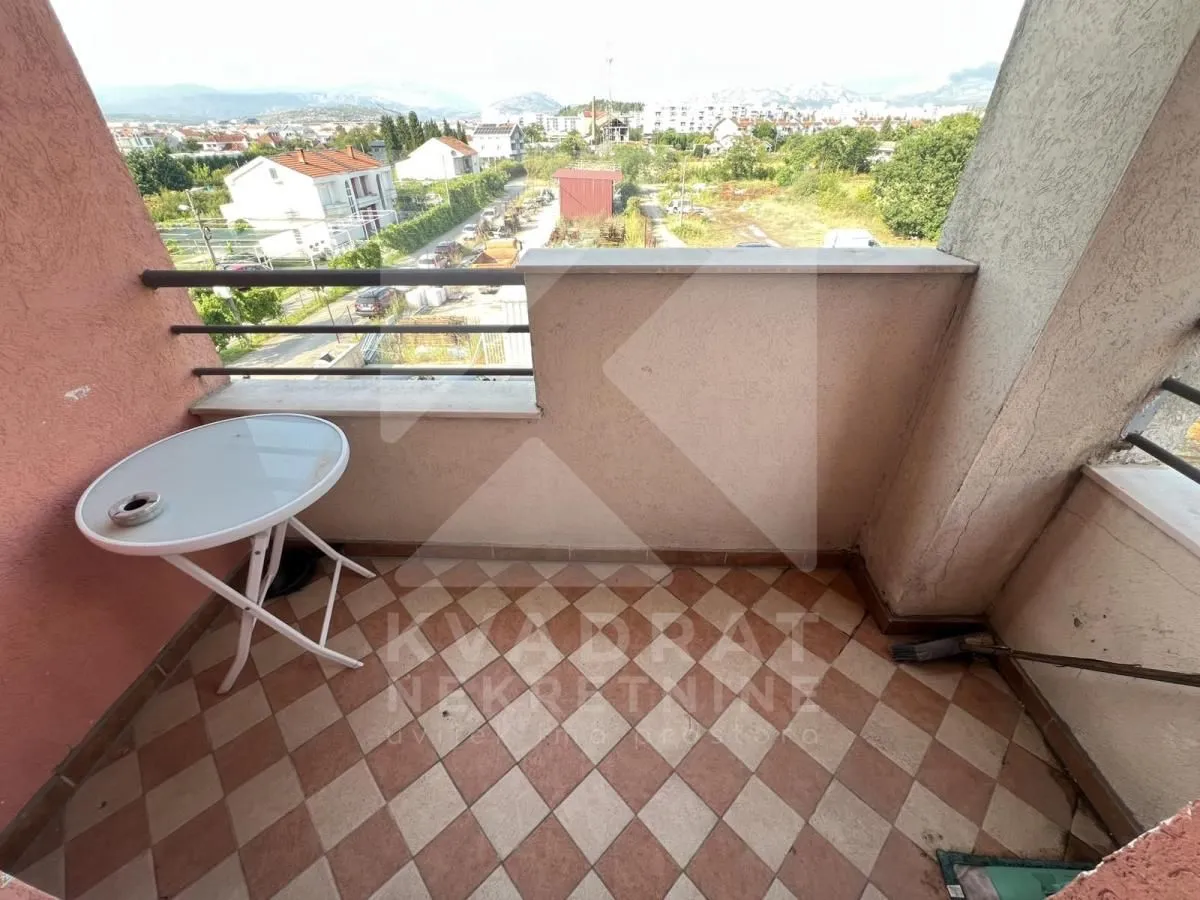Small tiled balcony with a small table and a view of the neighborhood and surroundings.