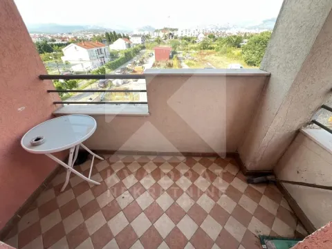 Small tiled balcony with a small table and a view of the neighborhood and surroundings. - image 13