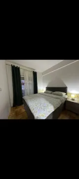 Furnished bedroom with a double bed, nightstands, and a window with dark curtains. - image 10