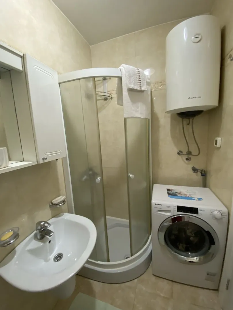 Small bathroom with a shower cabin, washing machine, and water heater.