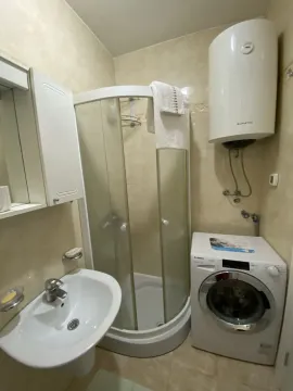 Small bathroom with a shower cabin, washing machine, and water heater. - image 5