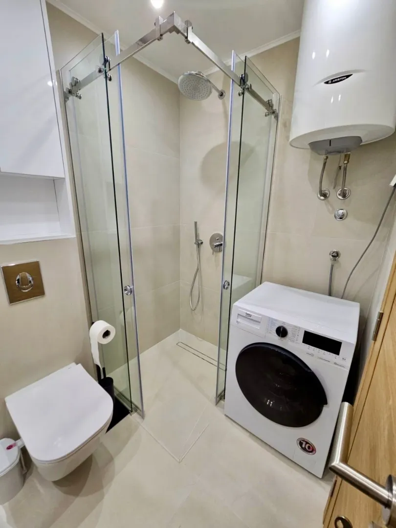 Kupatilo opremljeno tuš kabinom, WC šoljom i veš mašinom.