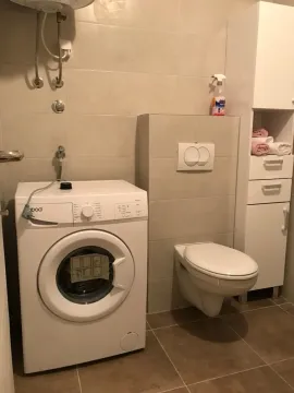 Manje kupatilo sa veš mašinom, WC šoljom i bijelim ormarićem. - image 11