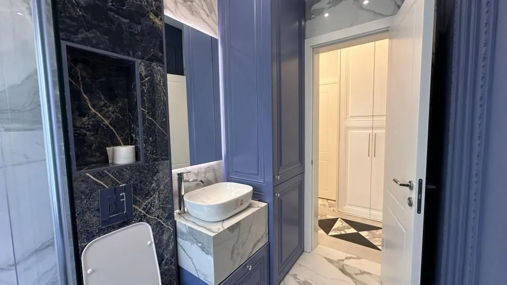 Moderno kupatilo sa umivaonikom i ugrađenim plavim elementima.