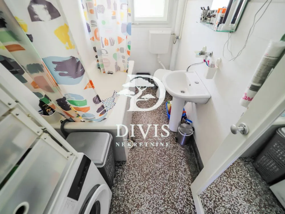 Small bathroom with a bathtub, washbasin, and washing machine.