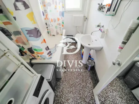 Small bathroom with a bathtub, washbasin, and washing machine. - image 18