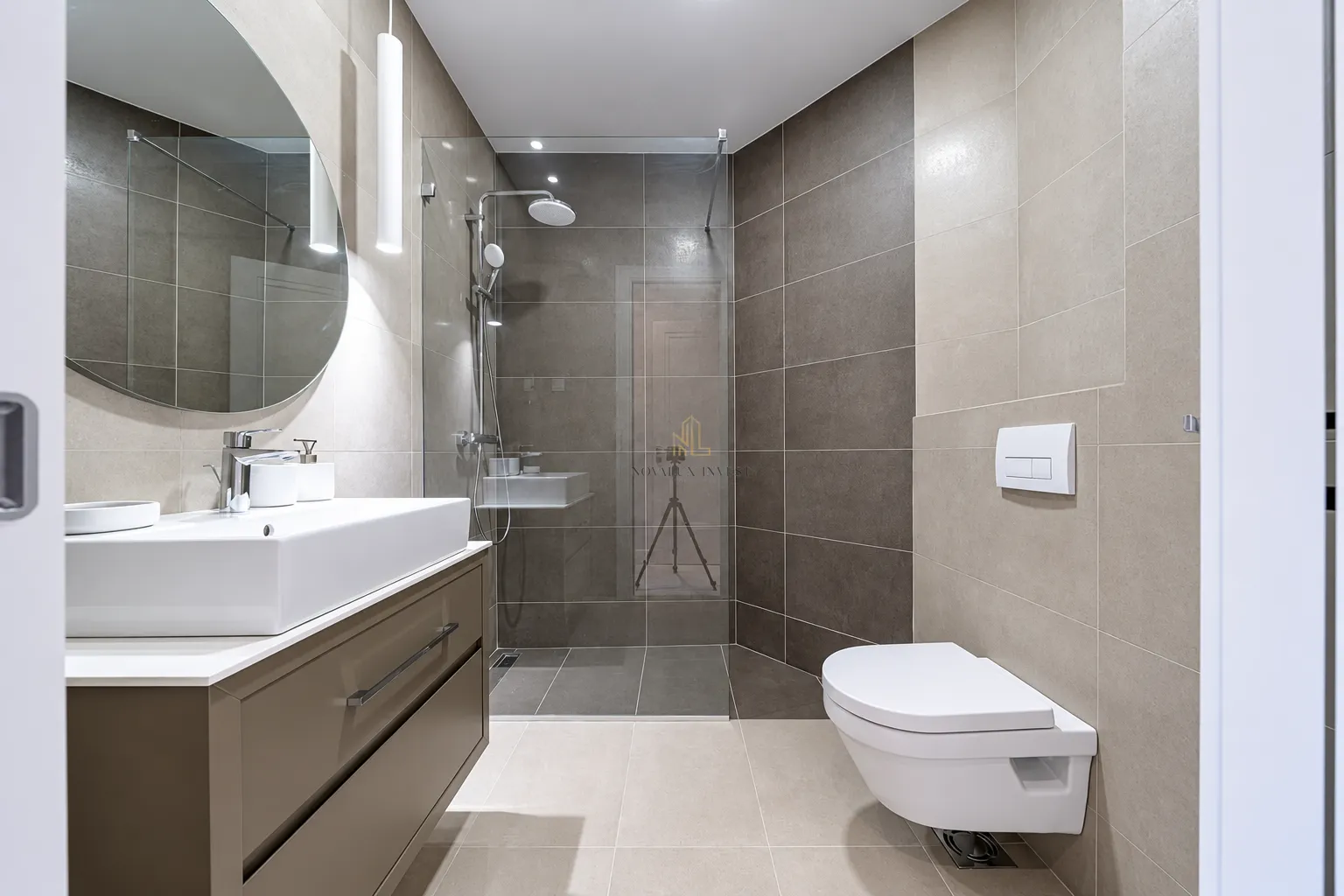 Modern bathroom equipped with a walk-in shower and washbasin.