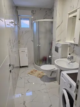Manje kupatilo sa tuš kabinom, umivaonikom, toaletom i veš mašinom obloženo mermernim pločicama. - image 11