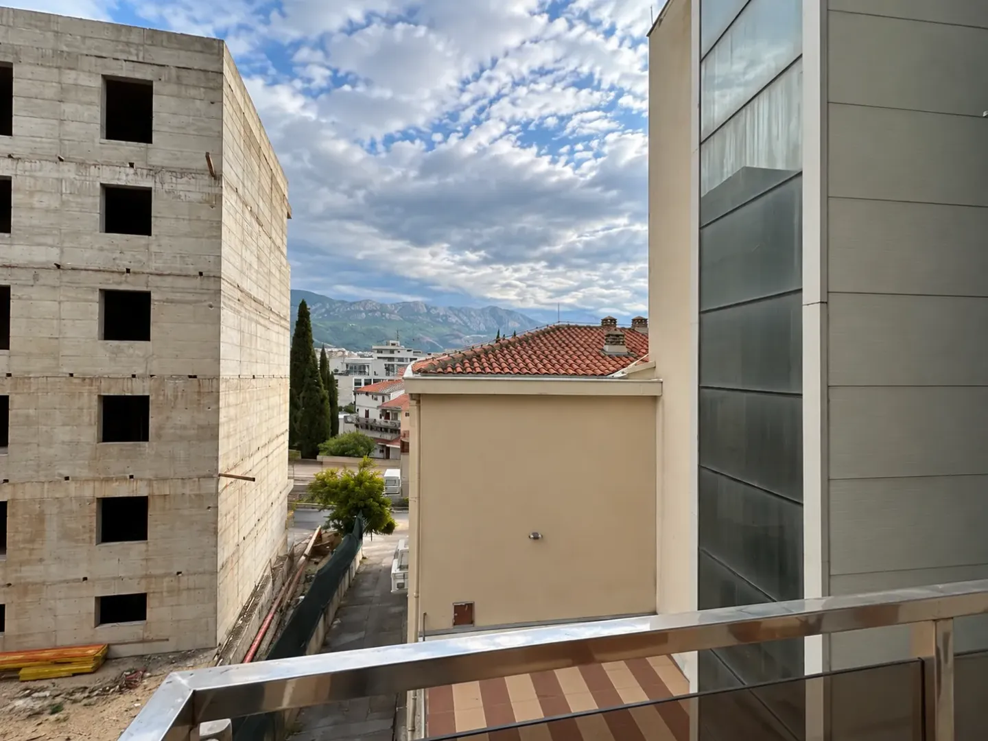 Pogled sa terase na okolne zgrade i planine u daljini.