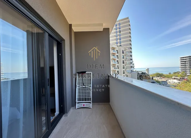 Modern balcony with a view of the sea and surrounding buildings.
