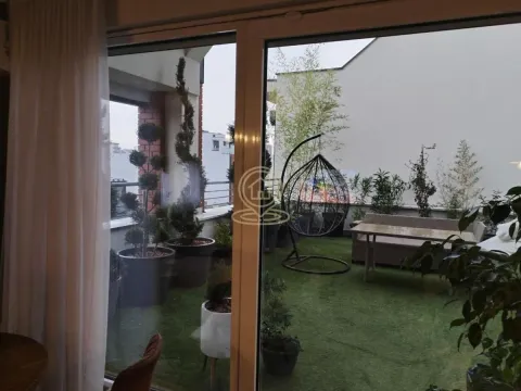 Pogled kroz balkonska vrata na uređenu terasu sa veštačkom travom i garniturom za sedenje. - image 3