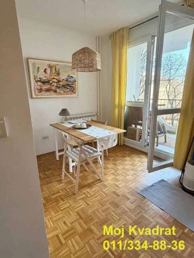 Trpezarija sa trpezarijskim stolom i stolicama i izlazom na terasu.