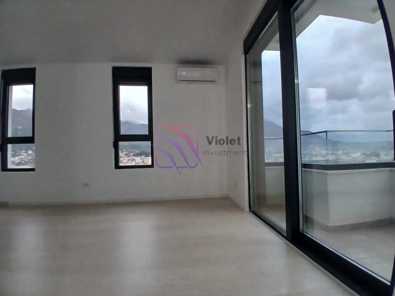 Prazna svijetla prostorija sa velikim staklenim površinama i izlazom na terasu.