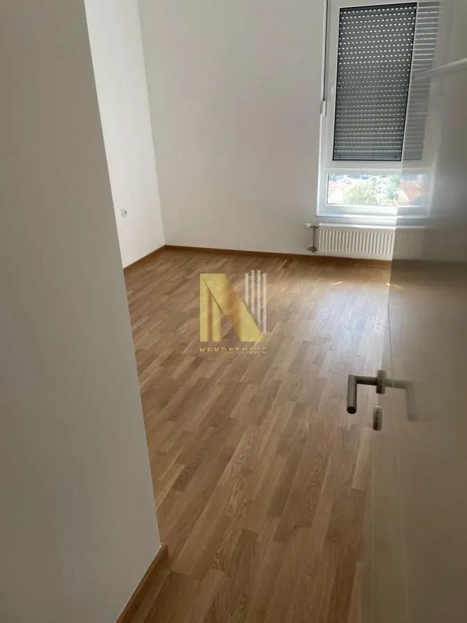 Prazna soba sa parketom i prozorom.