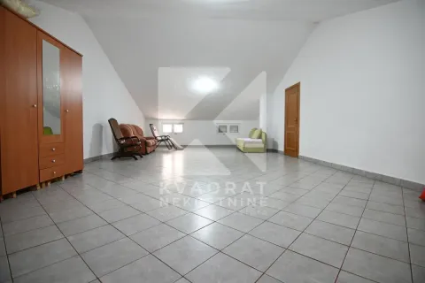 Spacious living room with a sloped ceiling, tiled floor and minimal furniture. - image 19