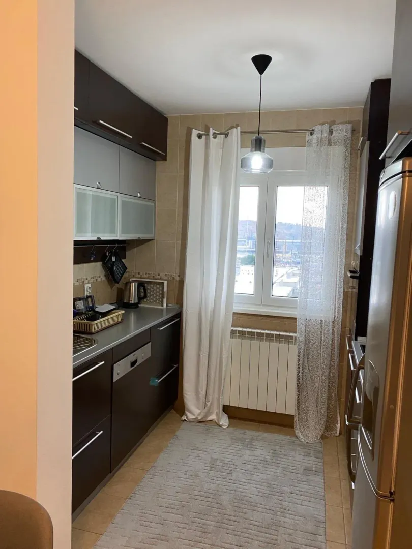 Manja kuhinja sa tamnim elementima i prozorom koji gleda na spoljašnjost.
