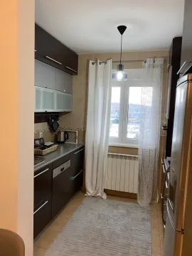 Manja kuhinja sa tamnim elementima i prozorom koji gleda na spoljašnjost. - image 5
